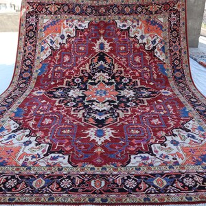 May include: A large, intricately patterned rug with a red, blue, and white color scheme. The rug has a central medallion with a geometric design and a border with floral motifs.