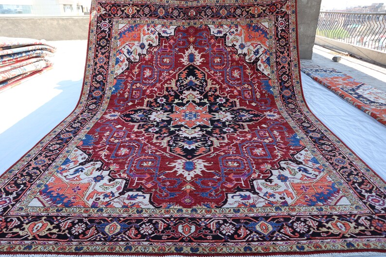 May include: A large, intricately patterned rug with a red, blue, and white color scheme. The rug has a central medallion with a geometric design and a border with floral motifs.