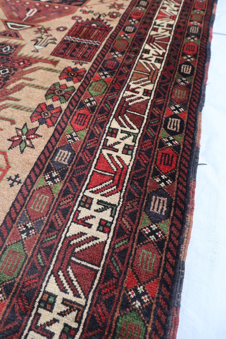 Pu&ograve; includere: Primo piano di un tappeto con un motivo geometrico dettagliato in tonalit&agrave; di rosso, verde, nero e bianco. Il tappeto ha un bordo con frange.