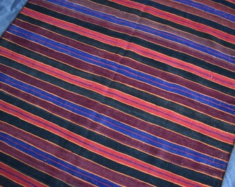 Puede incluir: Alfombra tejida a rayas con bandas alternas de negro, rojo, azul y marrón.