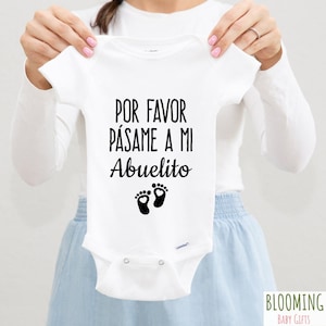 Könnte beinhalten: Weißer Baby Strampler mit schwarzem Text, der "Por favor pásame a mi Abuelito" lautet, mit einem Paar schwarzer Fußabdrücke mit Herzen in der Mitte.