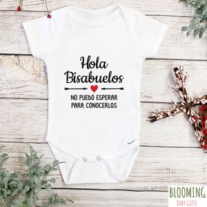 May include: White baby onesie with black text that reads "Hola Bisabuelos" with a red heart and arrows. The text below reads "No puedo esperar para conocerlos".