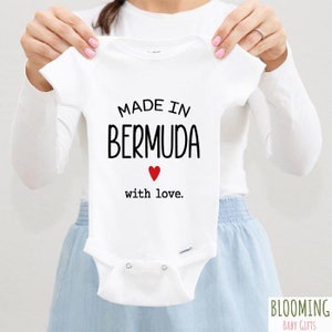 May include: White baby onesie with black text that reads "Made in Bermuda with love." A red heart is above the text "with love."