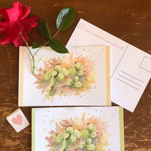 May include: Two watercolor paintings of prickly pear cactus with green pads and red fruit. The paintings are on white card stock with a light green border. The top painting has the text "Dianna Bradshaw 20" in pink cursive.