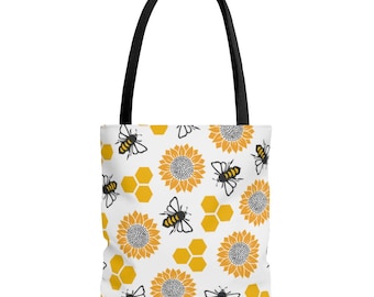 May include: A white tote bag with a repeating pattern of yellow sunflowers, black and yellow bees, and yellow honeycomb.