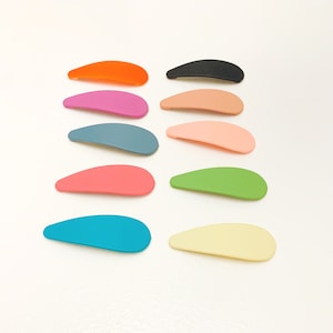 May include: A set of ten colorful plastic hair clips in various shades of pink, blue, green, orange, and yellow. The clips are all the same shape, a slightly curved rectangle.