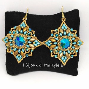 May include: A pair of gold and blue beaded earrings with a starburst design and crystal accents. The earrings are displayed on a black velvet background.