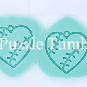 May include: Two light blue silicone molds shaped like hearts with a stitched design inside. The molds are approximately 2 inches in diameter.