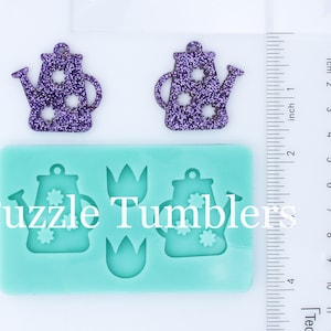 May include: A silicone mold for making resin crafts. The mold features two watering can designs and two tulip designs. The mold is light blue and has the text "Puzzle Tumblers" printed on it.