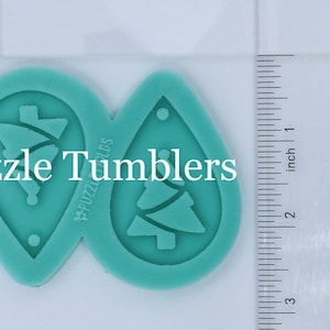 May include: Two teal-colored silicone molds for making earrings. Each mold is shaped like a teardrop and features a Christmas tree design. The molds are approximately 2 inches in length.