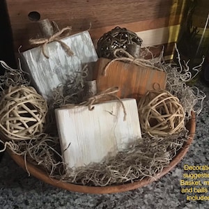 Pode incluir: Uma tigela de madeira cheia de musgo seco e bolas decorativas. A tigela contém três abóboras de madeira caiadas. Sugestão de decoração. Cesto, musgo e bolas não incluídas.