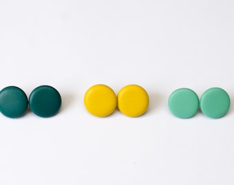 May include: Three pairs of round stud earrings in teal, yellow, and mint green.