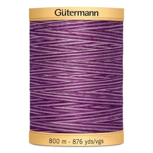 May include: A spool of Gütermann thread, in a striking purple hue with white detailing. The spool has beige ends, with the brand name "Gütermann" printed on the top. The spool contains 800 meters of thread.