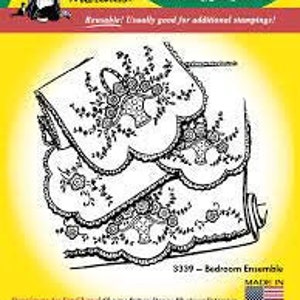 May include: Iron-on transfer design for a bedroom ensemble. The design features a floral motif with a basket of flowers and a scalloped edge. The transfer is reusable and can be used for additional stamping.
