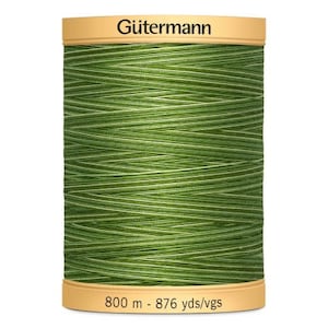 May include: A spool of Gütermann thread in a vibrant green colour with white accents. The spool has a beige label with the brand name and the text "800 m - 876 yds/vgs". This thread is suitable for various sewing projects.
