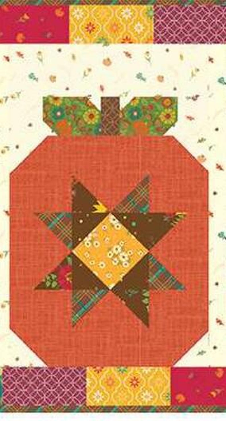 May include: A patchwork quilt block with a pumpkin design. The pumpkin is mainly orange with a starburst pattern in the centre, using brown, yellow, and floral fabrics. The top and bottom borders have patterned fabric strips.