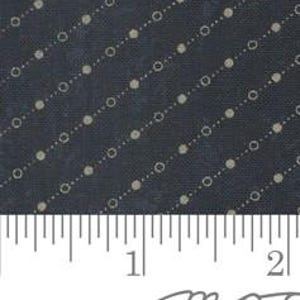 May include: Close-up of a navy blue fabric with a repeating pattern of small, off-white dots and circles arranged diagonally. A ruler with inch measurements is at the bottom of the image.