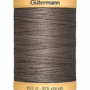 May include: A dark grey Gütermann thread spool. The spool has a tan label at the top with the brand name and a bottom label with the measurement of 800 m. The thread is tightly wound around the spool, ideal for sewing projects.