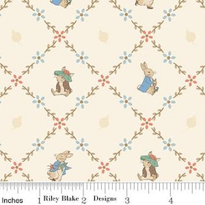 May include: Cream-colored fabric with a repeating pattern of bunnies, flowers, and leaves. The bunnies are wearing clothes and hats. The flowers are blue and red, and the leaves are a light tan color. A ruler in inches is at the bottom.