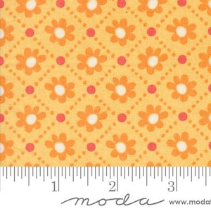 Pode incluir: Um tecido amarelo com um padrão repetitivo de pequenas flores laranja e pontos vermelhos. O tecido é medido com uma régua que lê "moda" no canto inferior direito.