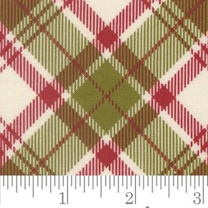 May include: A woven fabric featuring a diagonal plaid pattern in shades of olive green, dark brown, and red on a cream background. A white ruler is positioned at the bottom, showing a scale of three inches to indicate the size of the pattern repeat.
