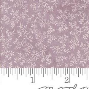 May include: A close-up of a fabric with a lavender background and a white floral pattern. The pattern features delicate vines and small leaves. A ruler is at the bottom, showing measurements in inches.
