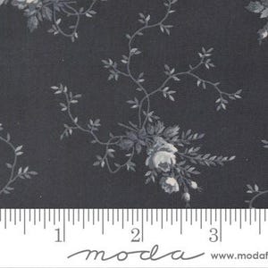Puede incluir: Una tela de color gris carbón oscuro con un patrón repetitivo de ramos de flores de color gris claro y delicadas enredaderas. Una regla blanca en la parte inferior muestra una escala de aproximadamente 9 cm a lo ancho de la tela.