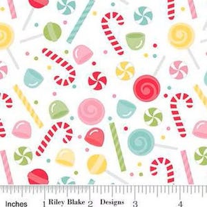 Op de afbeelding: Witte stof met een kleurrijk snoepjespatroon. Het ontwerp bevat rood-witte zuurstokken, roze en rode swirl snoepjes, lolly's en andere zoetigheden in roze, groen, geel en blauw. De tekst "Inches" en "Riley Blake Designs" is zichtbaar.