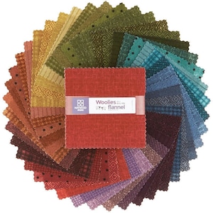May include: A collection of colorful flannel fabric squares in various shades of red, orange, yellow, green, blue, and purple. The squares are arranged in a circular pattern, with a central stack of red fabric squares held together by a band that reads "Woolies the Colors Flannel."