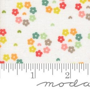 Op de afbeelding: Witte stof met een herhalend patroon van kleine, kleurrijke bloemen in een cirkelvormig ontwerp. De bloemen zijn in tinten roze, oranje, geel, groen en bruin.