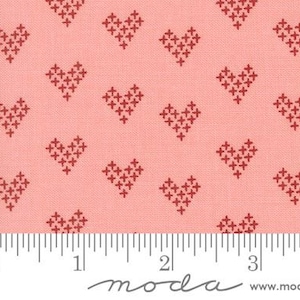 May include: Pink fabric with a repeating pattern of red stitched hearts. The fabric is measured with a ruler in inches.