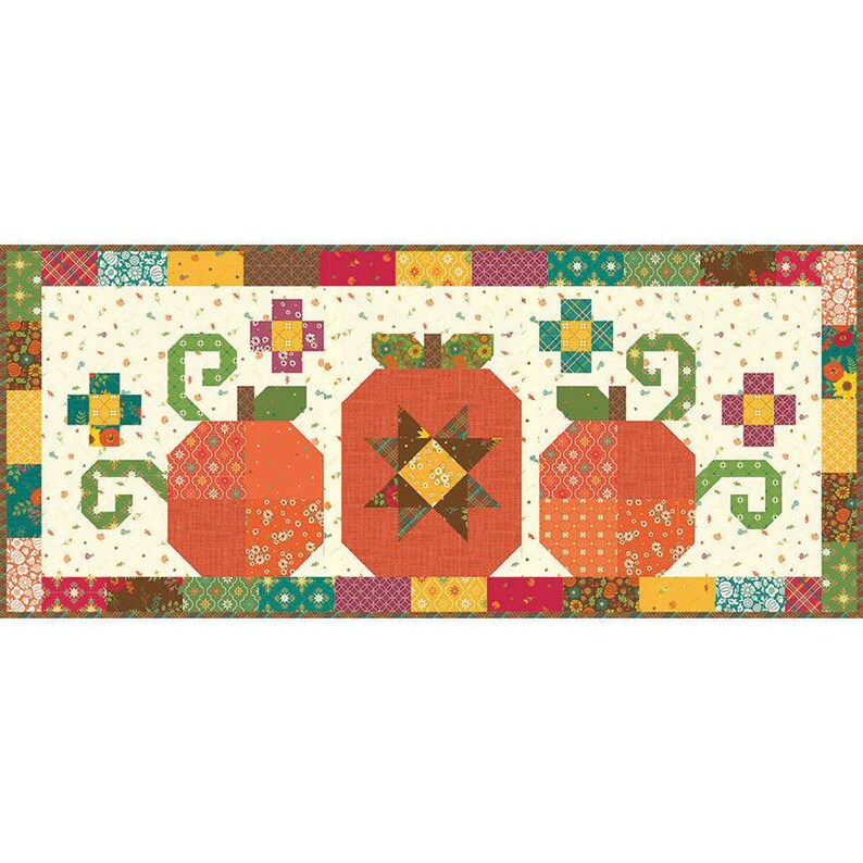 May include: A quilted table runner with three stylised orange pumpkins, green stems and curly vines. The pumpkins are set against a cream background with floral and leaf patterns. The border is a patchwork of autumn-themed fabrics.