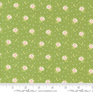 May include: Green fabric with a white polka dot pattern and a repeating pattern of small pink and white flowers. The fabric is marked with a ruler and the words "moda" and "www.modafabrics.com".