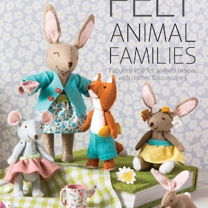 May include: A book titled "Felt Animal Families" by Corinne Lapierre, featuring a close-up of a group of felt animal toys, including a rabbit, a fox, a mouse, and a bunny, all dressed in colourful clothes and accessories. The book cover features a white background with a floral pattern.