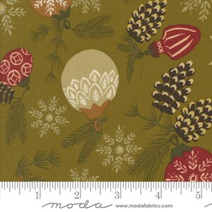 May include: Close-up of a fabric with a repeating Christmas-themed pattern. The design features ornaments, pinecones, snowflakes, and pine branches in shades of red, white, and green on an olive-green background. The fabric is measured with a centimetre ruler.