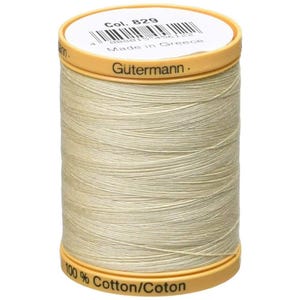 May include: A spool of Gütermann thread in a light beige colour. The spool has a yellow-gold top and bottom with the text "Gütermann" and "100% Cotton/Coton". The top label reads "Col. 829" and "Made in Greece".