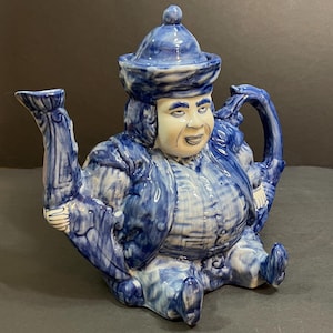 Peut inclure: Théière en céramique bleue et blanche en forme d'homme portant un chapeau. La théière a une expression fantaisiste et un design détaillé.