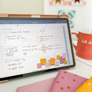 May include: A digital tablet displaying a sewing project plan with the title "Scrappy Cover Sample". The plan includes details like fabric colors, measurements, and design ideas. The tablet is on a white surface with fabric swatches in pink, orange, and yellow.