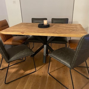 May include: A wooden dining table with a black metal base and four chairs. The table has a light wood finish and the chairs have black metal frames and dark brown leather seats.