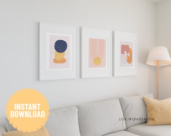 May include: Three abstract art prints in white frames, featuring geometric shapes in pink, yellow, blue, and orange. The prints are hung on a white wall above a gray couch with a yellow throw pillow.