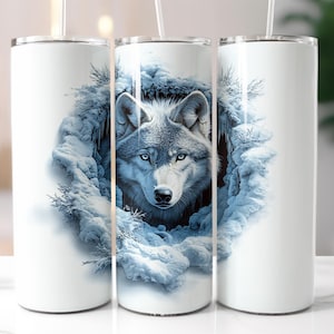 May include: White stainless steel tumbler with a wolf's face peeking out of a snowy cave. The wolf has blue eyes and a white and gray coat.