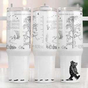 May include: A white stainless steel tumbler with a black and white illustration of Winnie the Pooh and Piglet from the book Winnie the Pooh. The tumbler has a black handle and a black lid. The text "Winnie the Pooh" is printed on the tumbler.