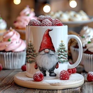 May include: White ceramic mug with a gnome illustration and red berries. The gnome is wearing a red hat and has a white beard. The mug is surrounded by red berries and a white background.