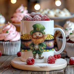 May include: White ceramic mug with a leprechaun design, green hat and suit, and pots of gold. The mug is filled with raspberries. The mug sits on a wooden coaster with icing sugar, surrounded by cupcakes.