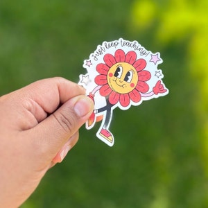 May include: A red and yellow cartoon flower with a smiling face and the text "Just keep teaching!"  The flower is wearing red shoes and has a pink star on its head.