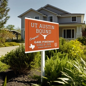 May include: A red and white yard sign with the text "UT Austin Bound" and "Congrats!" in a white cursive font. Below the text is a white silhouette of a longhorn steer. The sign also includes the text "Gabe Piwowar Class of 2028 BS Business Administration" and a small UT Austin logo.