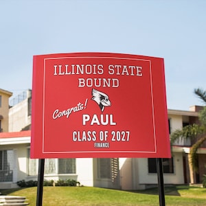 May include: Red and white yard sign with the text "Illinois State Bound" and a red bird logo. The sign also says "Congrats! Paul Class of 2027 Finance".