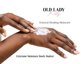 May include: A person's hand applying a white body butter cream to their skin. The text "Old Lady Katy Natural Healing Skincare" and "Extreme Moisture Body Butter" is visible in the image.