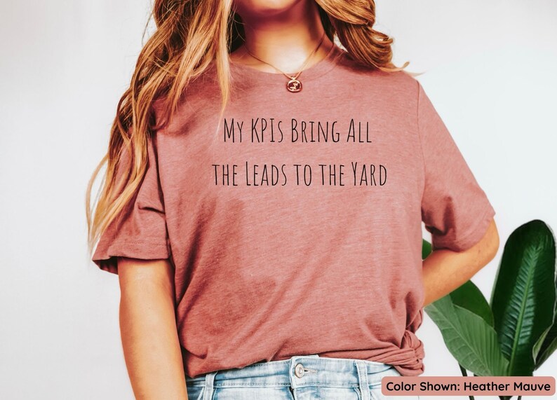 Pu&ograve; includere: Una t-shirt color malva melange con la scritta "My KPIs bring all the leads to the yard" stampata sul davanti.