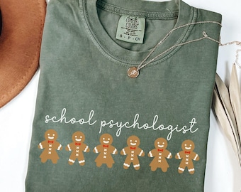 May include: A green t-shirt with the text "school psychologist" and a row of gingerbread men with red icing.